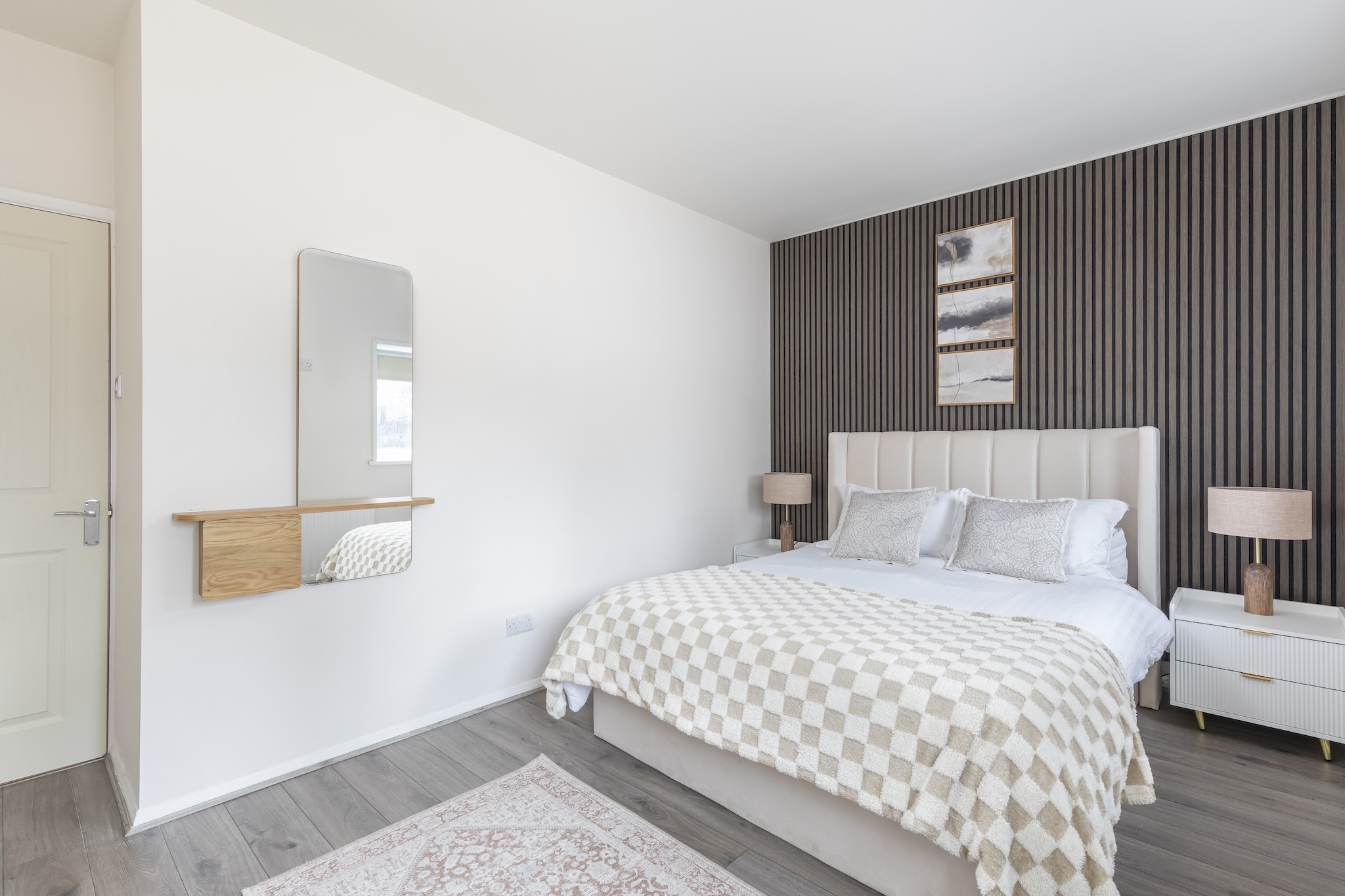 Master bedroom with upholstered headboard and slat-wood panelling