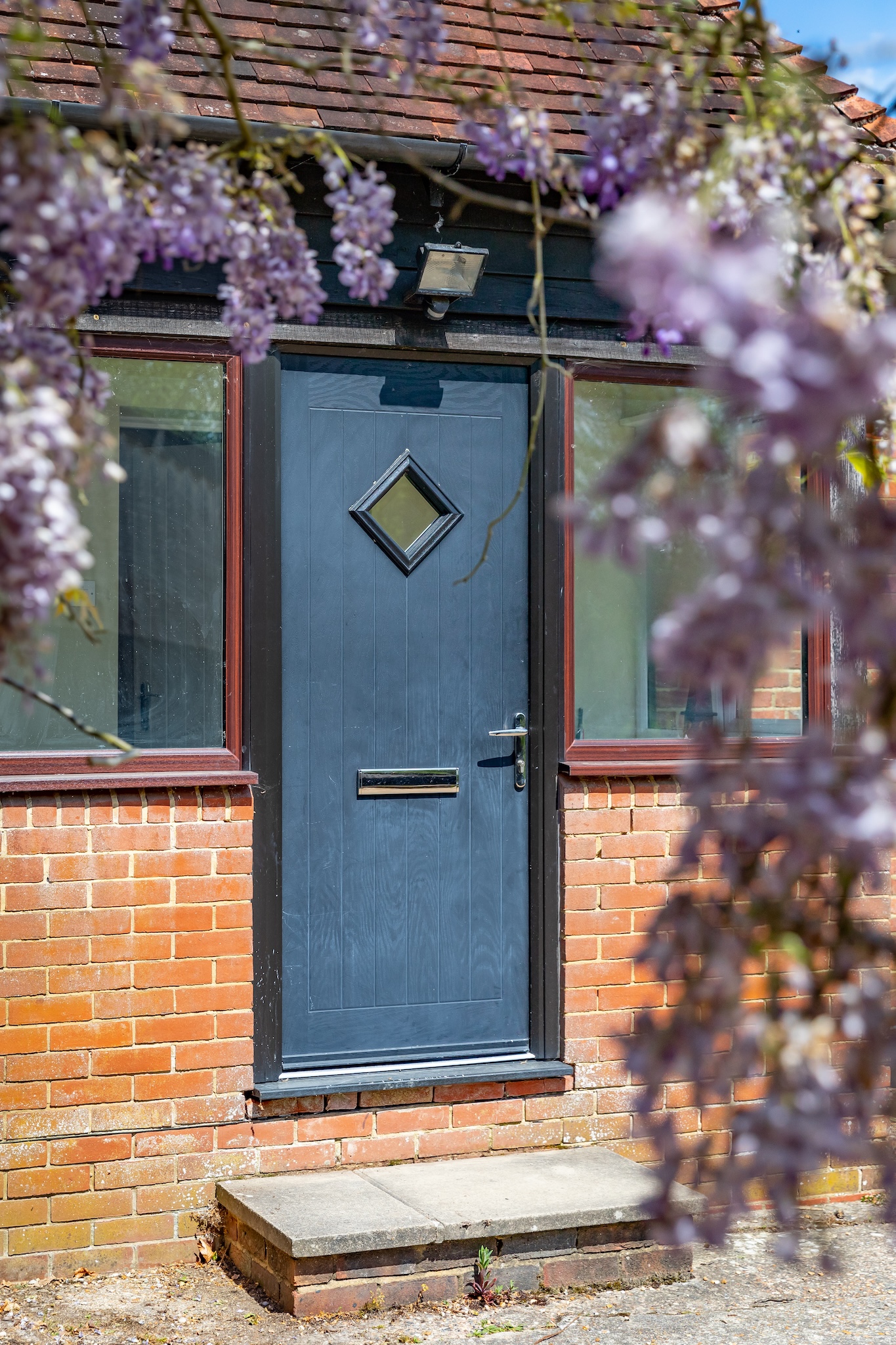The Dairy Cottage front door framed by wisteria in bloom