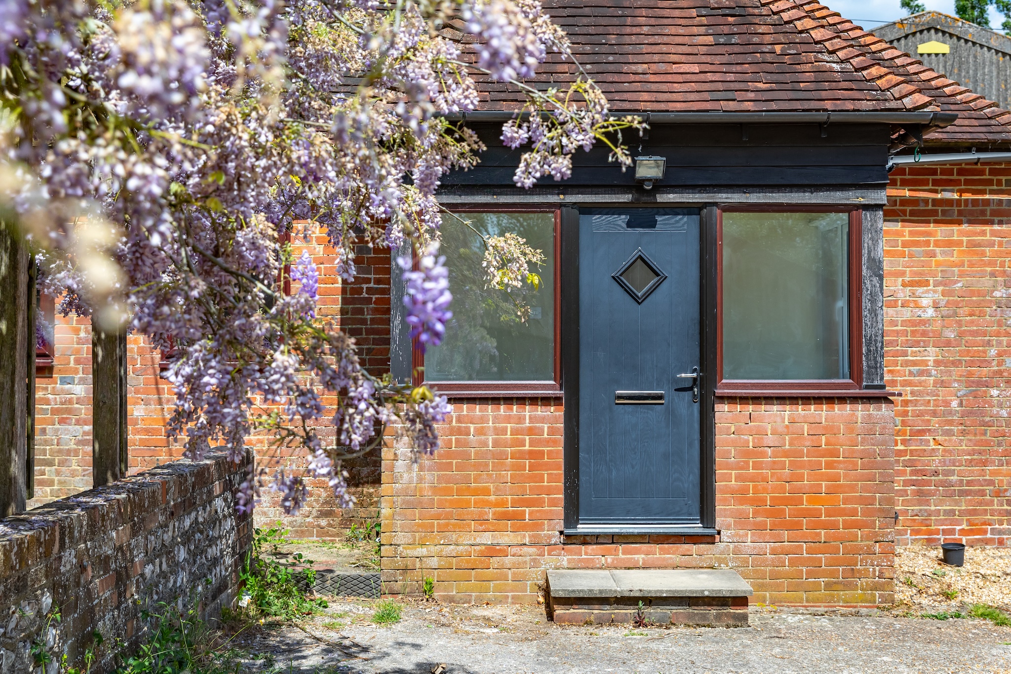 Wisteria-draped pergola leading along the side of the cottage