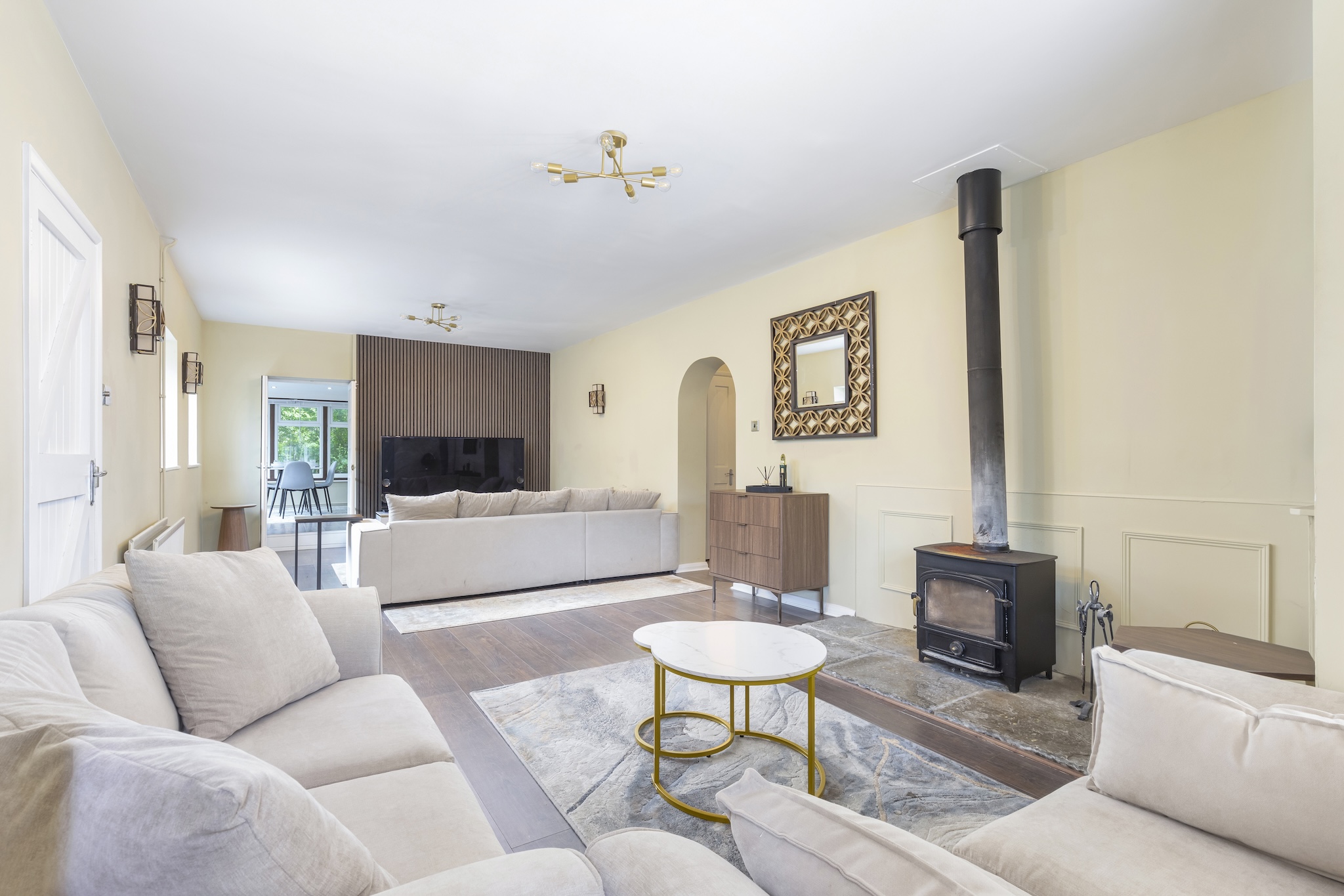 Open-plan living room with cream sofas, wood-burning stove and slate hearth